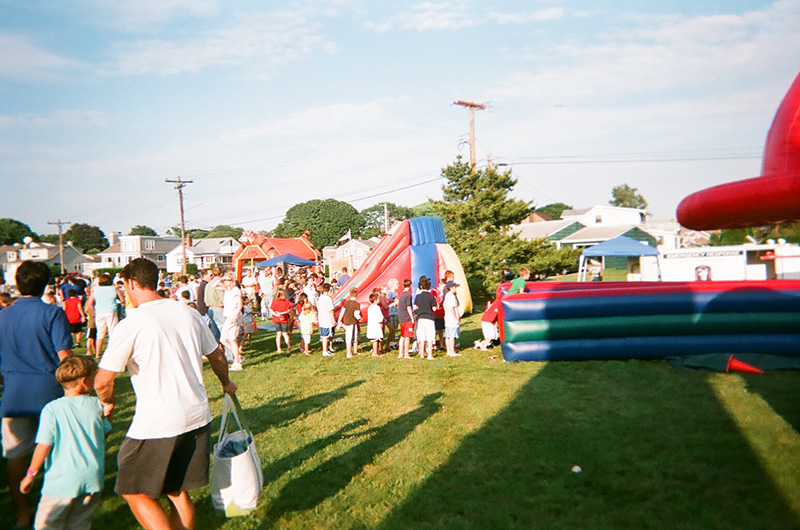 People of all ages around the Bungee Run and a group of bounce houses