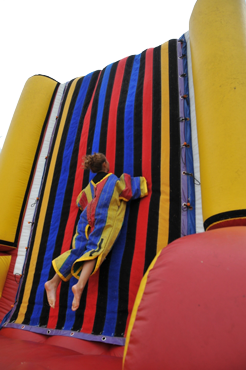 Person wearing a velcro suit on a sticky wall stuck until someone gets them down